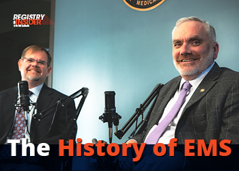 Two men sit in front of microphones, discussing the history of EMS. A logo is visible in the background.