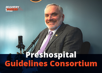 A smiling man in a suit sits in front of a microphone, with a blue background and text overlay reading "Preshospital Guidelines Consortium."